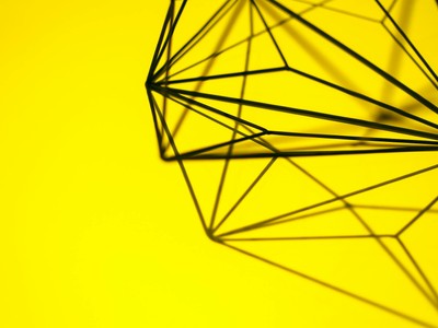Creative geometric structure casting intricate shadows on a vibrant yellow background.